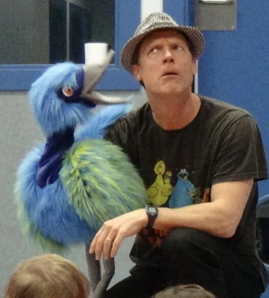 Actor de Chameleon Theatre dialogando con una marioneta de pájaro durante una función en inglés